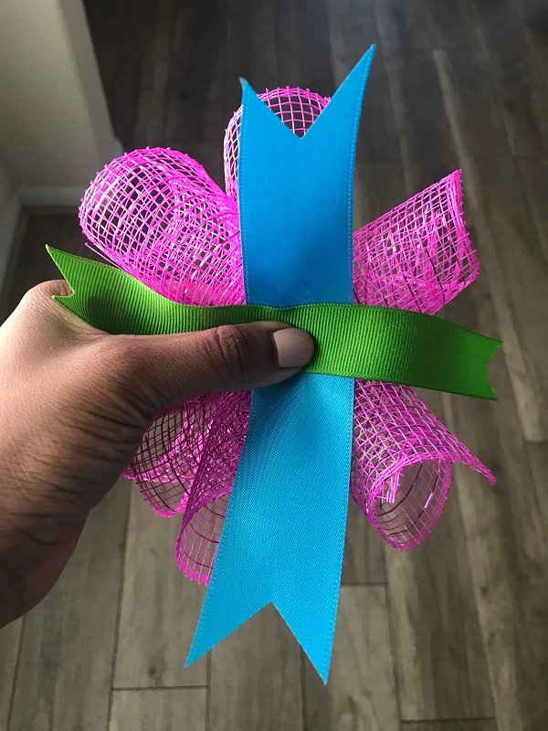 How To Add Ribbon To A Curly Deco Mesh Wreath | 3 pieces of rolled deco mesh, and 2 strips of ribbon, being prepared to add to wreath. 
