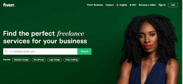 A screenshot of Fiverr's homepage. It has a forest green background with a Black woman in a navy blue sleeveless top. She has shoulder length kinky-curly hair, and is wearing red lipstick. There is a search bar, for finding freelancers, as well as other ways to navigate, such as become a seller, login, and changing the language and currency. It's in a Fiverr review article. 